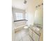 Bathroom with a granite vanity, blue-tile-trimmed tub, and a bright window at 1069 Universal Rest Pl, Kissimmee, FL 34744
