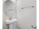 Small bathroom with pedestal sink, round mirror, and towel bar at 1740 Carnelian St, Deland, FL 32720