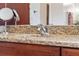 Bathroom sink with granite countertop and cherry wood cabinet is brightly lit at 1810 Markham Woods Rd, Longwood, FL 32779