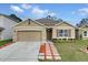 Tan house with brown shutters, landscaped yard, and a paved driveway at 965 Shady Tree Ln, Davenport, FL 33897