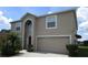 Two-story house with tan exterior, landscaping, and a two-car garage at 137 Milestone Dr, Haines City, FL 33844