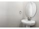 Elegant powder room featuring pedestal sink with modern fixtures and a round mirror at 211 Bull Frog Ln, Umatilla, FL 32784