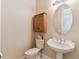 Charming half-bathroom featuring a pedestal sink, decorative fixtures, and a neutral color scheme at 256 New River Dr, Poinciana, FL 34759