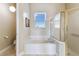 A tub is centered between a window and glass door shower in this neutral-toned bathroom at 256 New River Dr, Poinciana, FL 34759