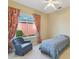 Cozy bedroom with an armchair and a single bed beneath a window dressed with patterned curtains at 256 New River Dr, Poinciana, FL 34759