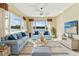 A relaxing living room features large windows, tile floors, a ceiling fan, and comfortable furniture at 256 New River Dr, Poinciana, FL 34759