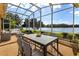 Relaxing screened-in patio overlooking a serene lake, complete with outdoor furniture for lounging and dining at 256 New River Dr, Poinciana, FL 34759