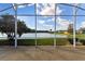 Exterior view from the lanai shows a serene lake framed by a screened enclosure and landscaping at 256 New River Dr, Poinciana, FL 34759