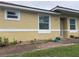 House exterior with light yellow painted stucco, a white door, and landscaping at 1645 Cumin Dr, Kissimmee, FL 34759