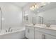 Bathroom featuring double sinks, a soaking tub, white cabinets, and a large mirror at 1695 Sugarbelle Cir, Mascotte, FL 34753