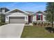 Charming home featuring a manicured lawn, stone accents, and a two-car garage at 1695 Sugarbelle Cir, Mascotte, FL 34753