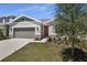 Charming home featuring a manicured lawn, stone accents, and a two-car garage at 1695 Sugarbelle Cir, Mascotte, FL 34753