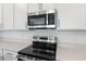 Close up of stainless steel oven and microwave, complemented by white cabinets and quartz countertop at 1695 Sugarbelle Cir, Mascotte, FL 34753