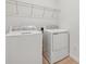 Bright laundry room features modern appliances, overhead shelving, and light-colored flooring at 1695 Sugarbelle Cir, Mascotte, FL 34753