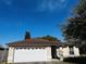 One-story house with brown roof, white garage door, and mature trees at 2704 Kendall Ave, Kissimmee, FL 34744