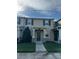 Tan two-story townhome with gray door, landscaping, and walkway at 2986 Aqua Virgo Loop, Orlando, FL 32837