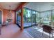 An enclosed patio featuring brick floors, comfortable seating, ceiling fan, and view of the backyard and lush landscaping at 521 Milano Rd, Kissimmee, FL 34759