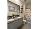 Well-lit bathroom featuring double vanity, decorative mirror, and charming seashell-themed shower curtain at 2459 Taloncrest Ct, Eagle Lake, FL 33839