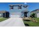 Two-story home with a manicured lawn and garden, two-car garage, and blue exterior at 2459 Taloncrest Ct, Eagle Lake, FL 33839