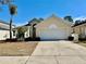 Tan house with a white garage door and landscaped yard at 931 Emerald Green Ct, Kissimmee, FL 34746