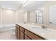 Bright bathroom featuring a double sink vanity, bathtub, and separate glass-enclosed shower at 9475 Randal Park Blvd, Orlando, FL 32832