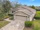 Tan house with a two-car garage and landscaped yard at 243 New River Dr, Kissimmee, FL 34759