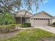 Tan house with a two-car garage and lush landscaping at 243 New River Dr, Kissimmee, FL 34759