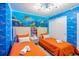 Two twin beds in a themed bedroom with ocean mural and orange bedding at 4154 Lana Ave, Davenport, FL 33897