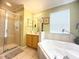 Bathroom featuring a glass enclosed shower, soaking tub, neutral tile, and lots of natural light at 8557 La Isla Dr, Kissimmee, FL 34747