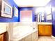 Bright bathroom featuring a garden tub with tile surround and blue walls at 8557 La Isla Dr, Kissimmee, FL 34747