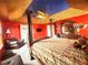 Bedroom showing a bed with columns, unique ceiling, seating area, neutral carpet, and bright red walls at 8557 La Isla Dr, Kissimmee, FL 34747