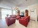 Spacious living room features neutral tile flooring, bright lighting, and four comfortable red chairs at 8557 La Isla Dr, Kissimmee, FL 34747