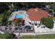 Aerial view of the pool area with palm trees, lounge chairs, tables, and manicured landscaping at 8557 La Isla Dr, Kissimmee, FL 34747
