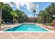 Community pool surrounded by lounge chairs, palm trees, and resort buildings under a sunny, blue sky at 8557 La Isla Dr, Kissimmee, FL 34747