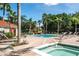 Community pool with palm trees, lounge chairs, and a spa on a sunny day at 8557 La Isla Dr, Kissimmee, FL 34747