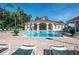 Spacious community pool with lounge chairs surrounding a central pool house on a sunny day at 8557 La Isla Dr, Kissimmee, FL 34747