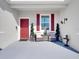 Inviting front porch with red door and wicker chairs at 905 Desmoines Way, Poinciana, FL 34759