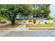 Gray house with a black door, driveway, and mature landscaping at 1504 Hummingbird Ln, Lakeland, FL 33801