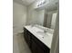 Bathroom with double vanity, a large mirror, and neutral tile flooring at 1655 Aspen Ave, Davenport, FL 33837