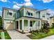 Two-story craftsman style home with green siding, white columns, and a paved driveway at 1829 Tropical Palms Cir Cir, Kissimmee, FL 34747