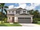 Two-story house with gray siding, stone accents, and a three-car garage at 219 Bull Frog Ln, Umatilla, FL 32784