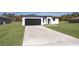 Modern single-story home features a black garage door, crisp white facade and well-manicured lawn at 2849 Sw 137Th Ln, Ocala, FL 34473