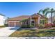 Tan house with two-car garage, palm trees, and landscaped yard at 3061 Palermo Rose Way, Kissimmee, FL 34746