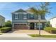 Two-story house with a green facade, brown garage door, and a well-manicured lawn at 370 Burma St, Kissimmee, FL 34747