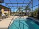 Inviting pool area with screened enclosure, patio furniture, and lush landscaping at 580 Cantabria Dr, Davenport, FL 33837