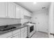 Bright laundry room with white cabinets, granite countertops, and a double sink at 832 Marion Oaks Mnr, Ocala, FL 34473