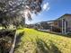 Spacious backyard features a screened-in pool area, lush green grass, and mature trees for outdoor enjoyment at 1717 Clubhouse Cv, Haines City, FL 33844