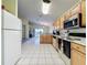 Well-lit kitchen boasts white tile floors, wooden cabinetry, and modern appliances for a functional cooking experience at 1717 Clubhouse Cv, Haines City, FL 33844