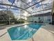 Sparkling pool inside screen enclosure offers refreshing escape with beautiful sky backdrop at 1717 Clubhouse Cv, Haines City, FL 33844