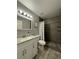 Clean bathroom with a white vanity, gray shower, and wood-look floor at 3036 Parkway Blvd # 104, Kissimmee, FL 34747